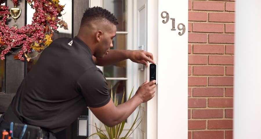 Vivint tech installing a doorbell camera at the front of a home