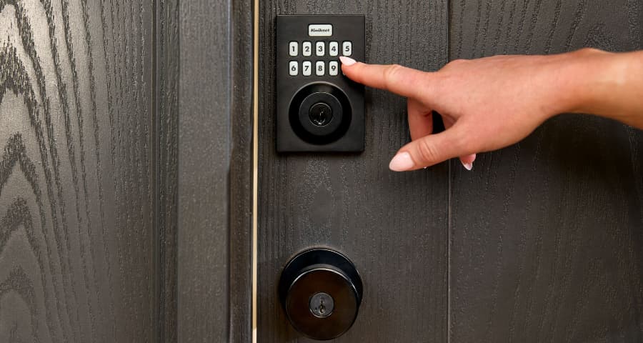 Homeowner touching the keypad of a Vivint smart lock from Kwikset